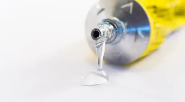 Goutte de colle polyuréthane sortant d'un tube métallique. Utile pour enlever colle polyuréthane tenace.