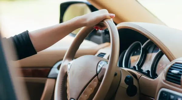Dłoń na kierownicy, czuć drgania na kierownicy przy 100 km/h. Wnętrze luksusowego samochodu.