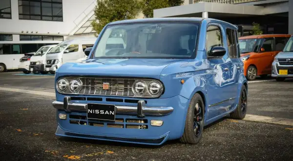 Niebieski Nissan Cube z chromowanymi zderzakami i grillem, obniżonym zawieszeniem i czarnymi felgami.