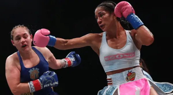 A boxer lands a powerful jab, her opponent reeling from the impact. The intensity of the fight is palpable, showcasing the raw emotion and skill involved in boxing terms.