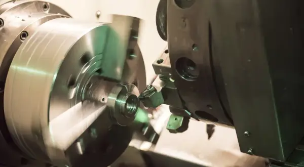 Precyzyjne toczenie aluminium na obrabiarce CNC. Metalowy element obraca się, a narzędzie precyzyjnie nadaje mu kształt.