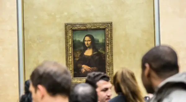Słynny obraz Mona Lisa da Vinci, otoczony tłumem widzów w muzeum.