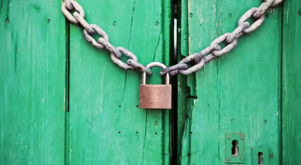 Puerta verde cerrada con cadena y candado. Un símbolo de que se puede quitar el usufructo de una vivienda.