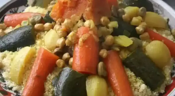 Un plat coloré de recette couscous avec carottes, courgettes, pois chiches et pommes de terre.