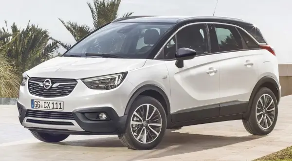 Biały Opel Crossland z czarnym dachem, zaparkowany na tarasie z palmami w tle. Wiele pozytywnych opinii o tym modelu.