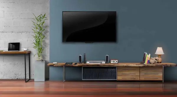 Moderner fernseher im wohnzimmer, daneben ein schlichtes Sideboard mit Deko und Büchern.