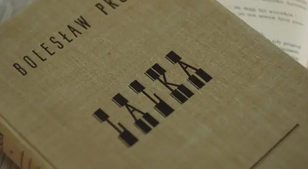 Okładka książki Bolesława Prusa "Lalka", która ukazuje motyw cierpienia w literaturze.