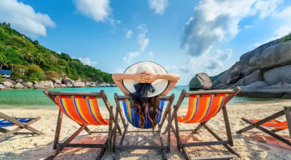 Relaks na plaży z widokiem na turkusowe morze i zielone wzgórza. Idealne miejsce, by odpocząć i zastanowić się, co robić w wakacje.