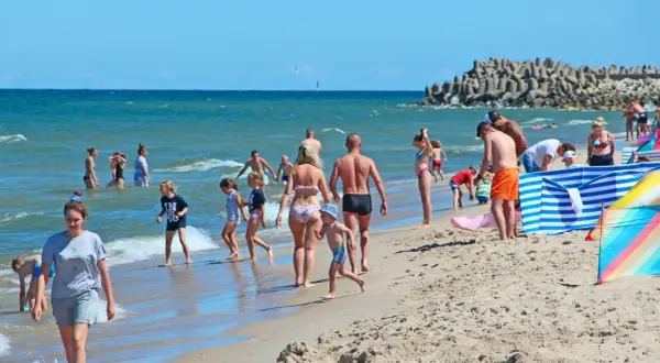 Ludzie odpoczywają na plaży nad Bałtykiem w słoneczny dzień.