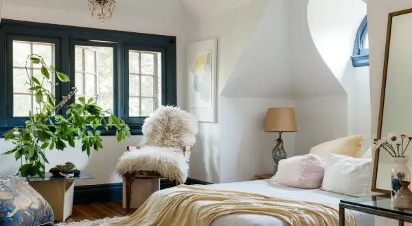 A cozy bedroom with a fluffy chair, plush pillows, and a soft throw blanket. Learn how to create a cozy bedroom with these inviting elements.