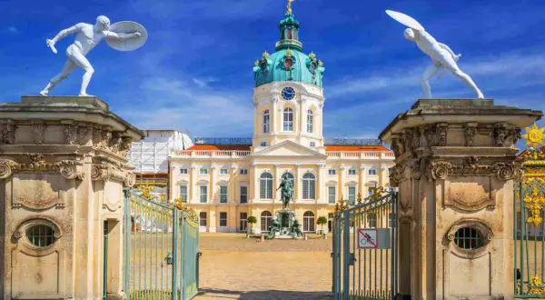 Pałac Charlottenburg w Berlinie, z jego kopułą i bogatymi zdobieniami, zachwyca w stylu na końcu baroku. Dwie białe rzeźby wojowników strzegą wejścia.