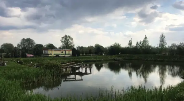 Łowisko Cicha Woda Niedrzwica Duża: spokojna tafla wody, przytulny domek i drewniany pomost.