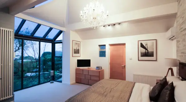 Habitación moderna con grandes ventanales que dan a un jardín. Ideas para como hacer un balcón en una casa ya construida.