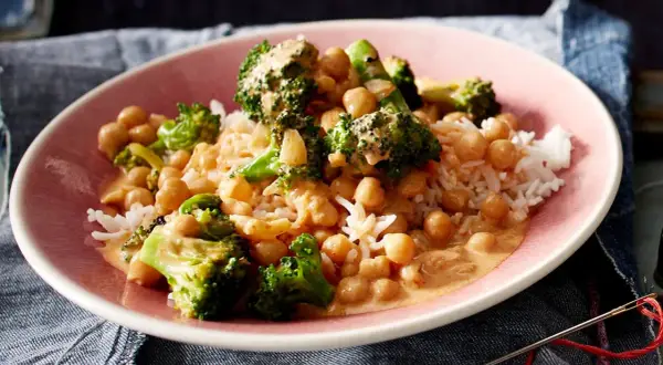 Ein Teller mit Reis, Kichererbsen und Brokkoli in cremiger Sauce. Ein leckeres Gericht, das zeigt, wie vielseitig Kichererbsen-Rezepte sein können.