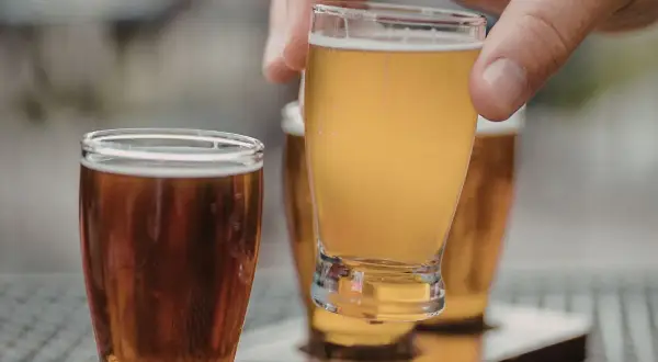 Assaggio di una fresca italian pale ale dorata, con un'altra birra ambrata in primo piano.