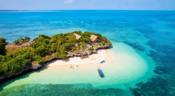 Rajska wyspa na Zanzibarze z turkusową wodą i chatkami. Zastanawiasz się, ile kosztuje wycieczka na Zanzibar?