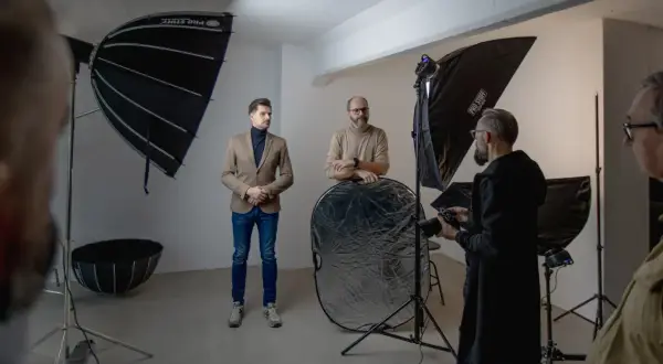W studiu fotograficznym mężczyźni przygotowują się do sesji. Wrota do świata fotografii otwierają się dzięki profesjonalnemu sprzętowi.