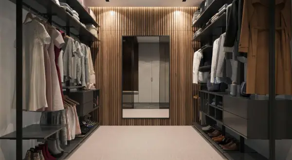Elegancka mini garderoba w pokoju z wieszakami pełnymi ubrań, półkami z butami i lustrem na tle drewnianej ściany.