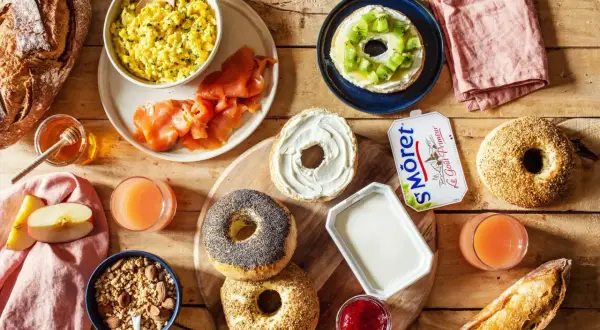 Un petit déjeuner peu calorique avec œufs brouillés, saumon fumé, bagels, fromage frais, fruits et jus.