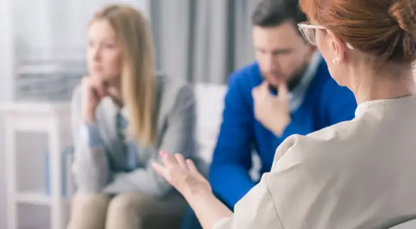 Terapeutka prowadzi interwencję kryzysową z parą. Kobieta i mężczyzna siedzą zamyśleni, szukając wsparcia.