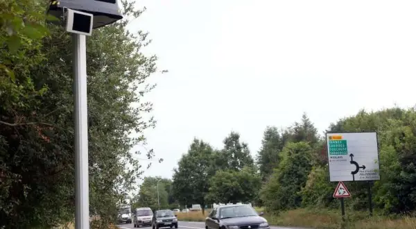 Un radar leurre sur un poteau, avec des voitures sur la route et un panneau de signalisation.