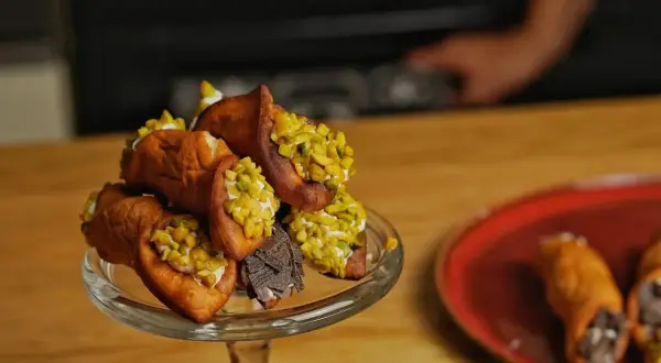 Ein Glasständer voller Cannoli, garniert mit Pistazien und Schokolade. Ein köstliches Cannoli-Rezept zum Nachmachen.
