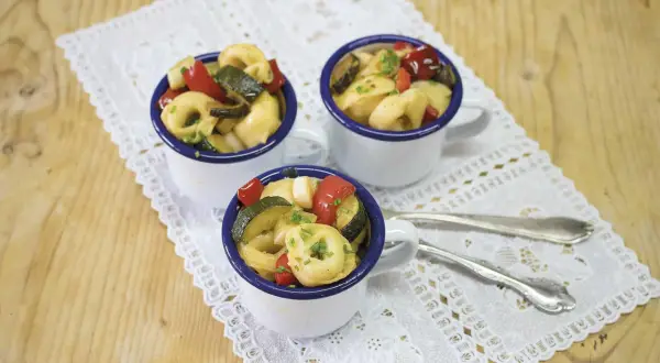 Drei Tassen mit Tortellini-Salat, garniert mit frischen Kräutern. Perfekt für die **10 besten Salate** zum Sommerfest.