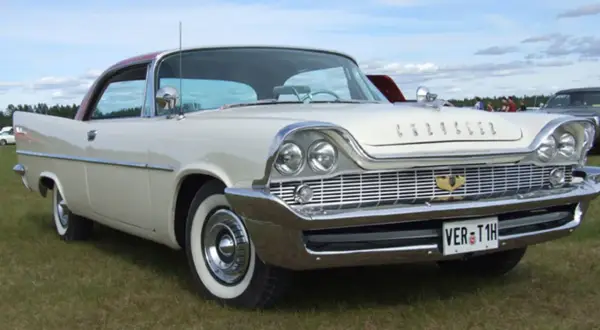 Vit Chrysler 58 med rött tak, blanka kromdetaljer och vit sidovägg på däcken. Bilen står på en gräsmatta.