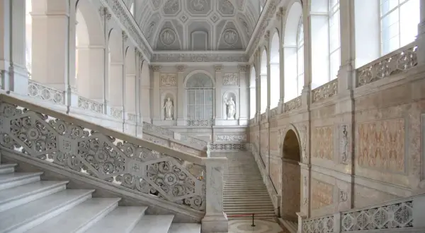 Scalinata monumentale del palazzo reale Napoli, con marmi bianchi e decorazioni barocche.