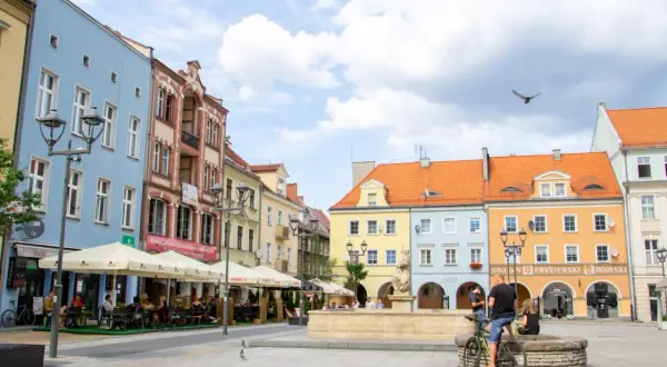 Kolorowy rynek w Gliwicach, idealne miejsce na weekendowe atrakcje. Ludzie siedzą w ogródkach kawiarnianych, a w tle widać zabytkowe kamienice.