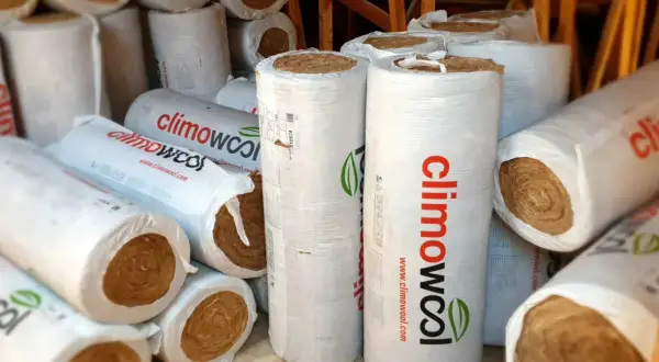 Zwoje wełny mineralnej, gotowe do utylizacji lub ponownego wykorzystania. Materiał izolacyjny w opakowaniach z logo "climowool".