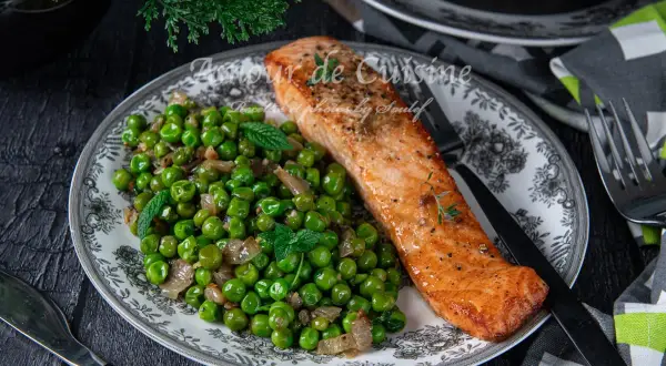 Filet de saumon poêlé servi avec une poêlée de petits pois et oignons, garnie de menthe fraîche. Une recette simple et savoureuse.