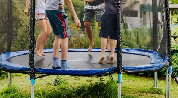 Dzieci skaczą na trampolinie, świetna zabawa i aktywność fizyczna. Czy trampolina jest zdrowa dla dzieci? Tak, rozwija koordynację i kondycję.