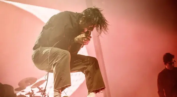 Chino Moreno z Deftones na koncercie w Polsce, w ogniu czerwonych świateł, śpiewa z pasją.