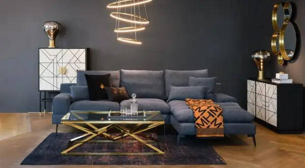 Nowoczesny, **soft loft salon** z szarą sofą, złotym stolikiem kawowym i designerską lampą.
