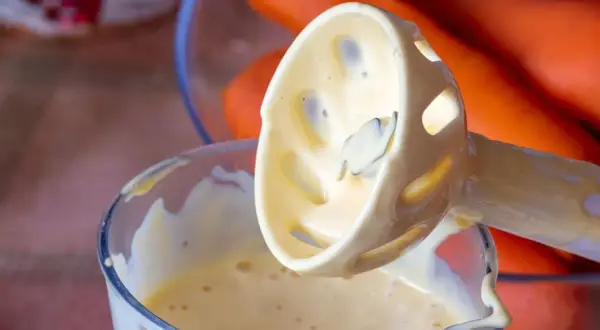 Batidora de inmersión con mayonesa casera cremosa, lista para acompañar unas zanahorias frescas.