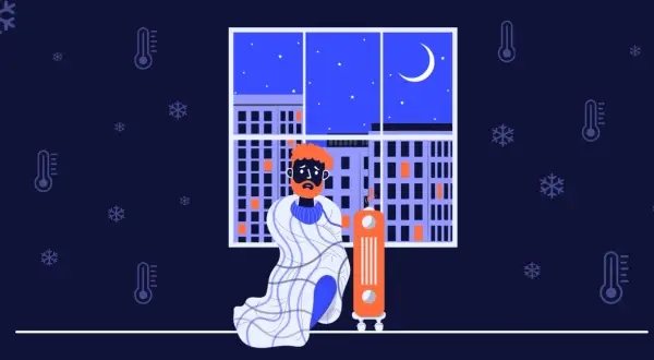 En man med orange hår och skägg sitter insvept i en filt bredvid en element. Utanför fönstret syns en stad i mörker med snöflingor och termometrar som visar att det är kallt i huset.