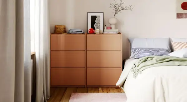 Modernes schlafzimmer design mit orangefarbenen Kommoden, einem Bett mit gestreiften Kissen und einer grünen Decke.