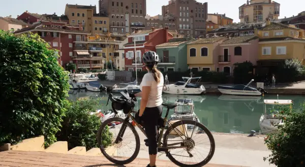 Ciclista en un puerto con casas de colores y barcos. Perfecta para descubrir las **rutas bici Valencia**.