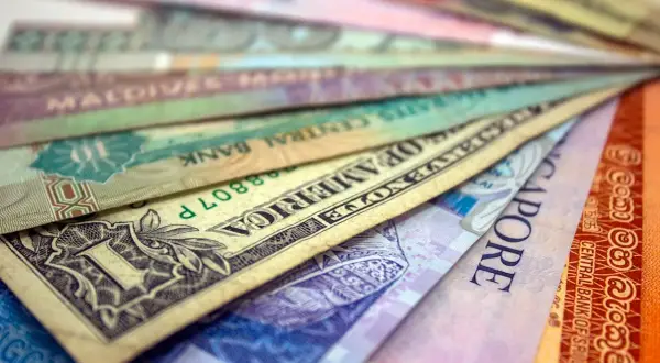 Różne waluty świata ułożone wachlarzowo, od dolara amerykańskiego po banknoty z Singapuru i Sri Lanki. Ile jest walut na świecie? Tyle, ile widzisz tutaj i jeszcze więcej!