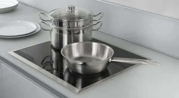 Pentole e padelle in acciaio inox pronte per cucinare su piastra a induzione.