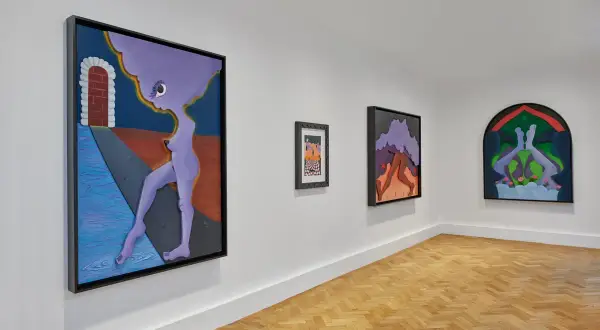 Gallery wall featuring surreal artworks by Alexandria Smith, including a purple figure by a brick archway and abstract forms.
