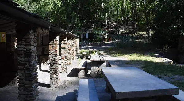 Merendero Laujar, un lugar ideal para disfrutar de un picnic rodeado de naturaleza. Mesas de piedra y madera bajo un techo rústico.