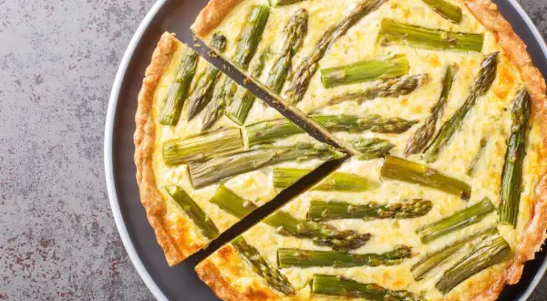 Eine köstliche Spargel Quiche mit einem goldbraunen Teigrand und saftiger Füllung, belegt mit frischem Spargel.