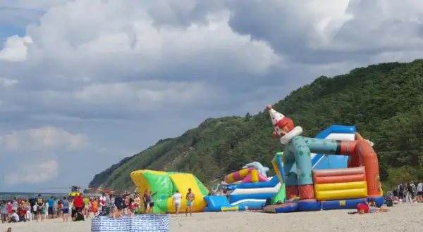 Kolorowe dmuchańce na plaży w Międzyzdrojach to świetne atrakcje dla dzieci. Wesoły klaun zaprasza do zabawy.