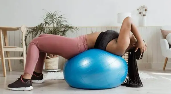 Femme faisant des exercices pour comment faire des abdos avec un ballon de gym bleu.