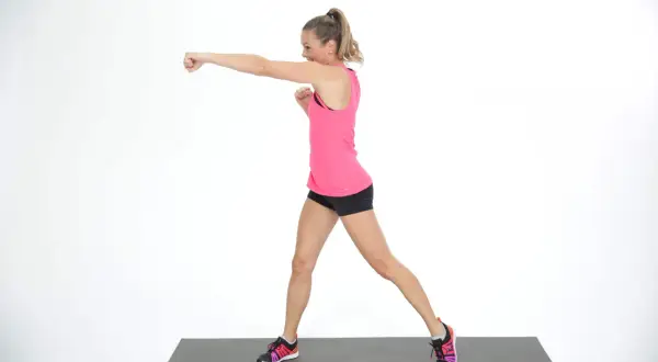 Woman in pink tank top and black shorts performs an undercut punch on a mat.