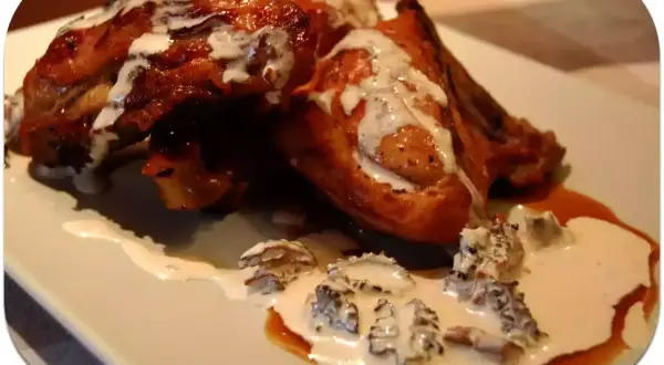 Pollo dorado bañado en una cremosa salsa de colmenillas, con trozos de hongo visibles.