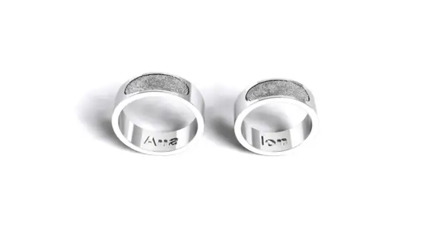 Dos anillos de plata grabados con huellas dactilares y nombres: "Ana" y "Ian". Un símbolo de amor eterno para rodear el dedo.