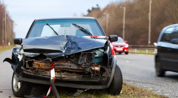 Un coche negro destrozado en la carretera, parece que fue un accidente grave. Un punto negro en la carretera que nadie quiere ver.